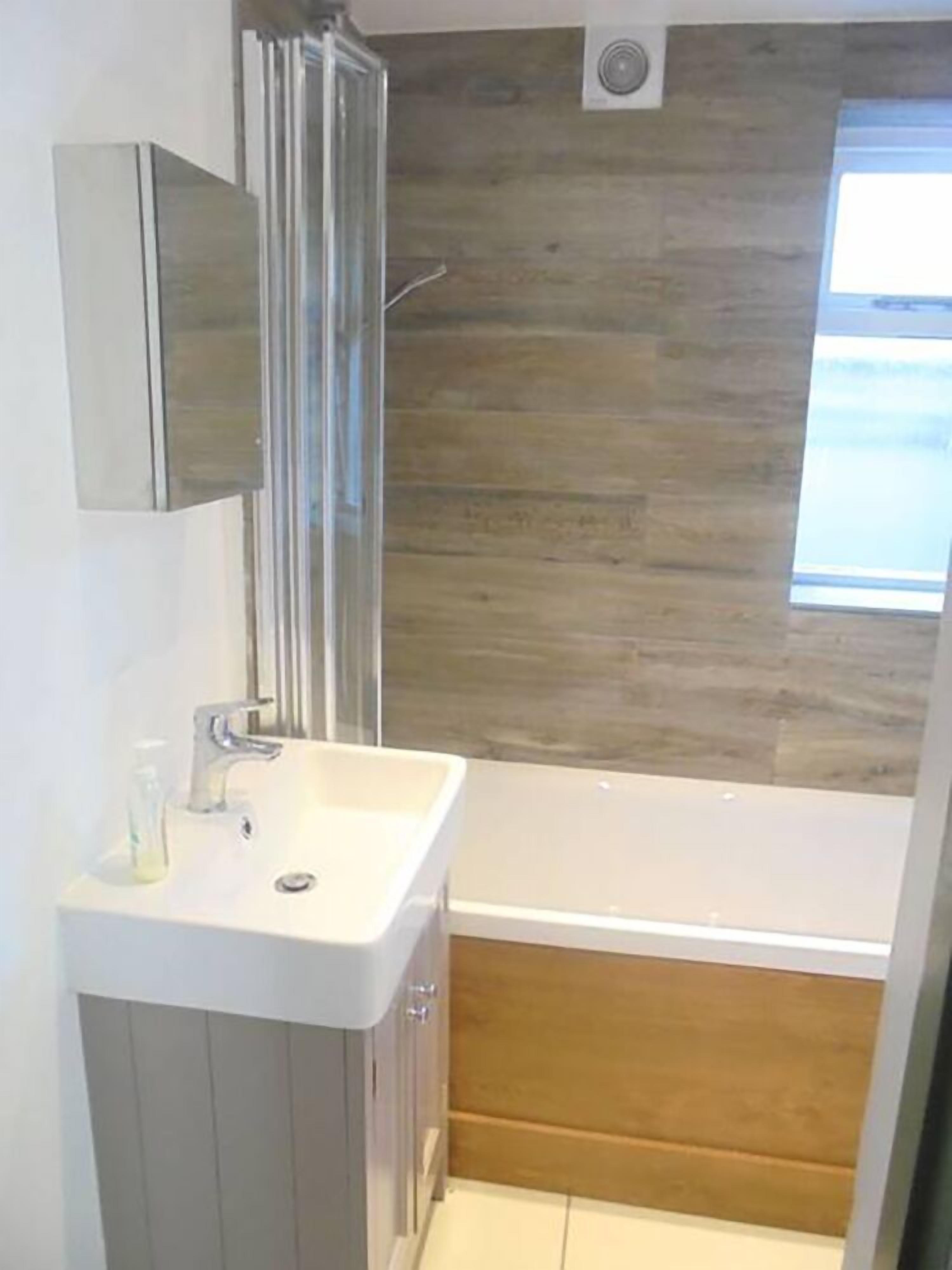 Ein modernes Badezimmer mit Waschbecken, Spiegel und Dusche in Weiß.