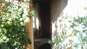 Un passatge estret cap a una habitació amb un paviment d'estries, una porta de fusta i una flor vermella al primer pla.