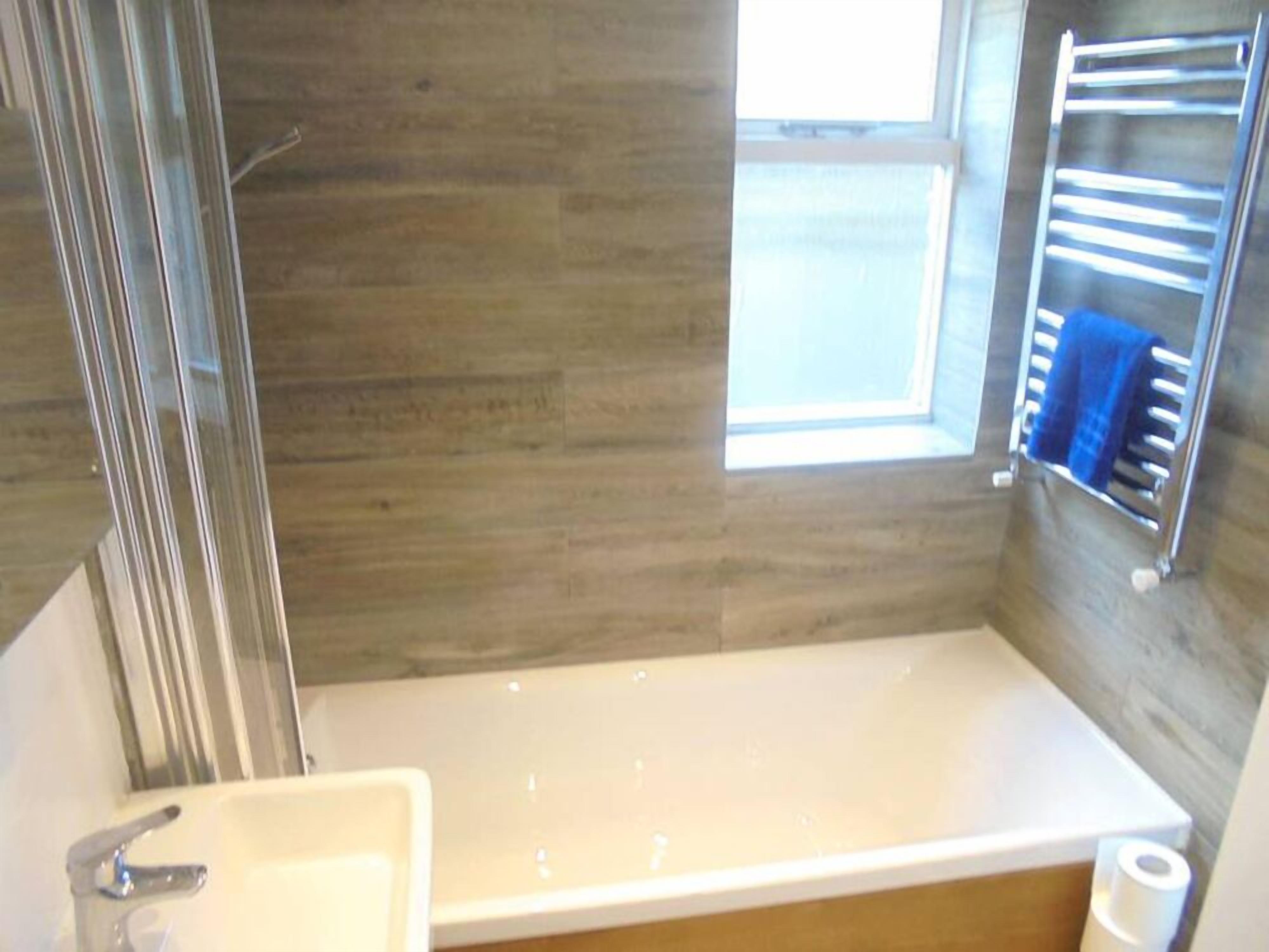 A bathroom with a bathtub, a sink, and a window.