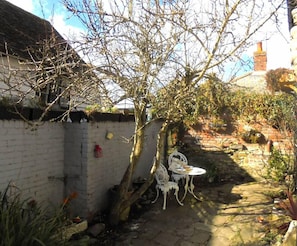 A narrow stone pathway leading to a white brick wall with a tree in the center.
