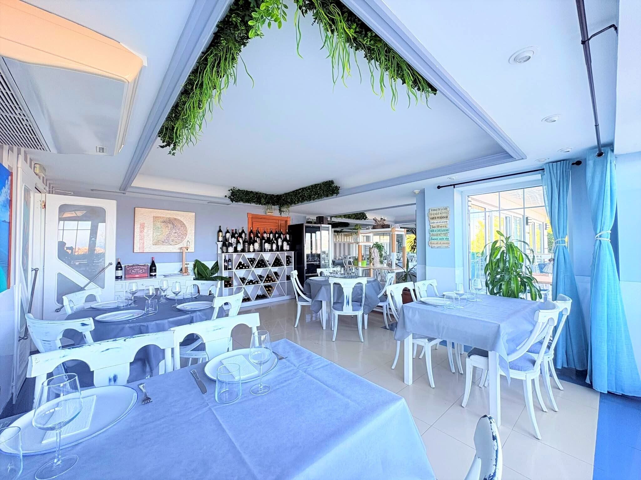 A restaurant with multiple tables, a wine rack, and a view of the outdoors.