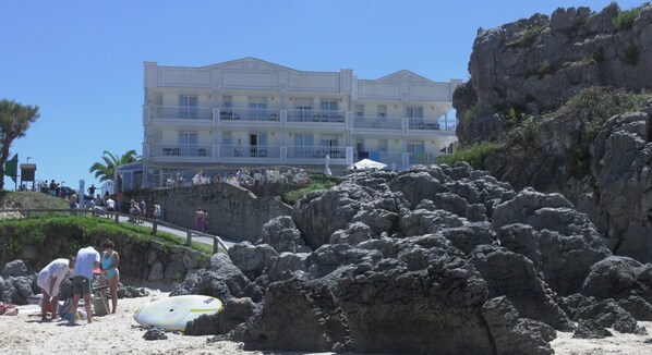 A beachfront hotel with multiple balconies, a rocky shoreline, and a clear blue sky. - Hotel Pineda Playa (Noja)