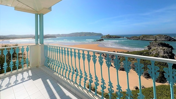 Un balcón con vistas a una playa y un litoral rocoso.