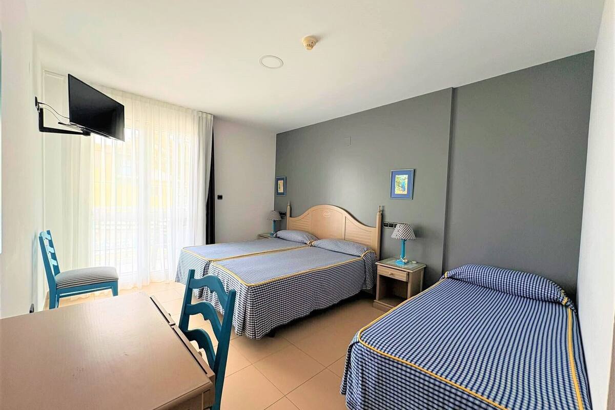 A hotel room with two beds, a TV, a table, and chairs.