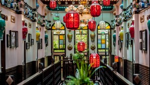 A traditional interior with wooden railings, red lanterns, and various framed items on the walls. - Songkhla Tae Raek Antique Hotel (Songkhla)