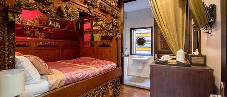 A traditional room with a wooden bed, ornate headboard, and a small bedside table with a lamp.