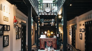 An interior with a reception desk, framed pictures, and a sign reading 'Antique Hotel.' - Songkhla Tae Raek Antique Hotel (Songkhla)