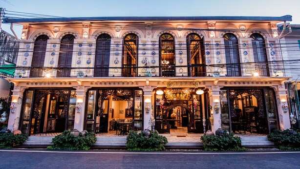 A historic building with multiple arched windows, a central entrance with a staircase, and a balcony with railings. - Songkhla Tae Raek Antique Hotel (Songkhla)