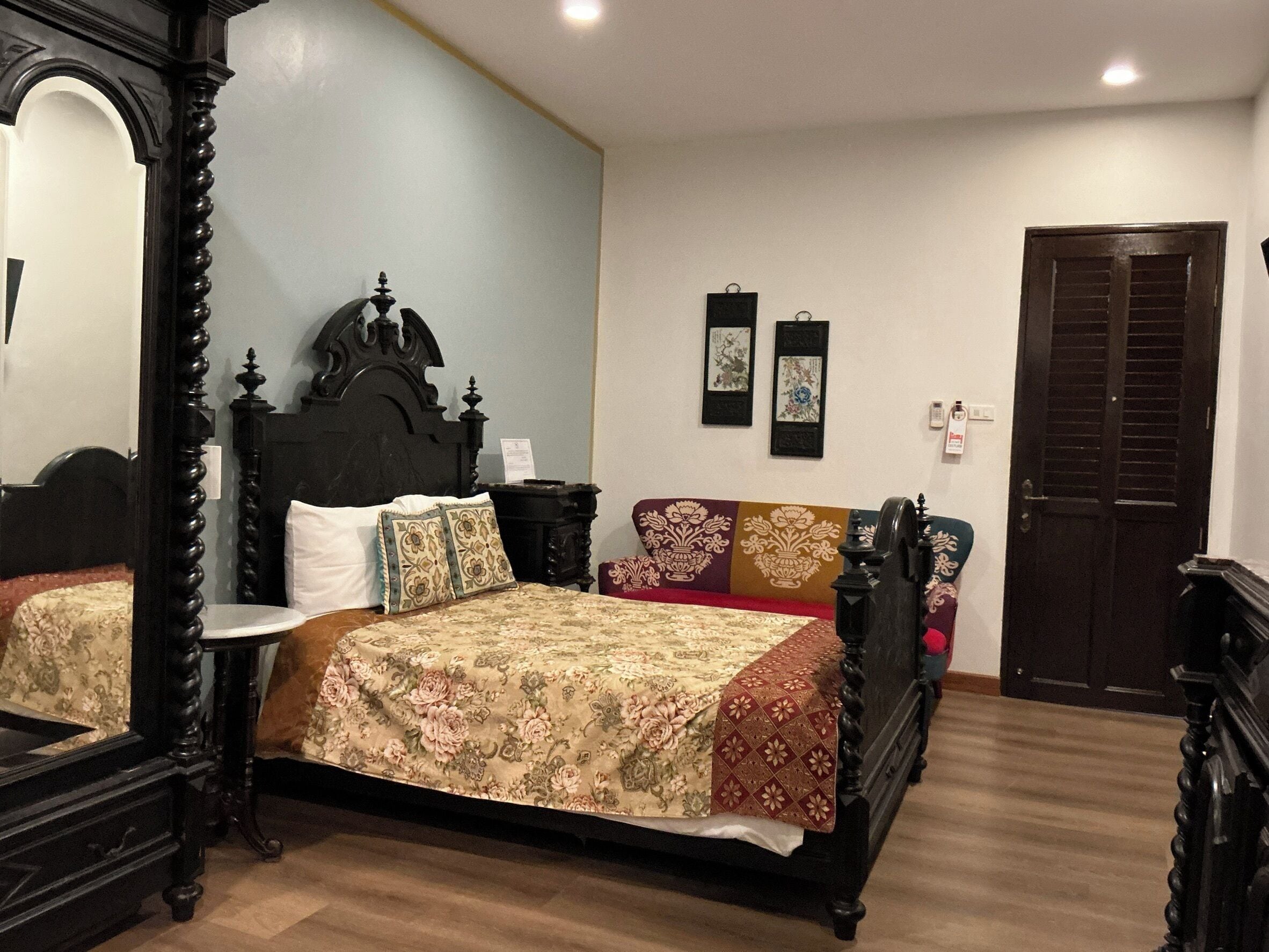 Un dormitorio con cama con dosel, una mesita de noche, un espejo y una puerta.