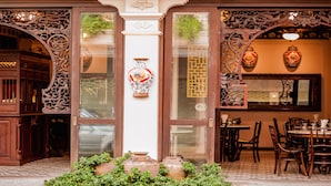 An ornate entrance with traditional Chinese architectural elements, a large decorative vase, and a dining area with wooden furniture. - Songkhla Tae Raek Antique Hotel (Songkhla)