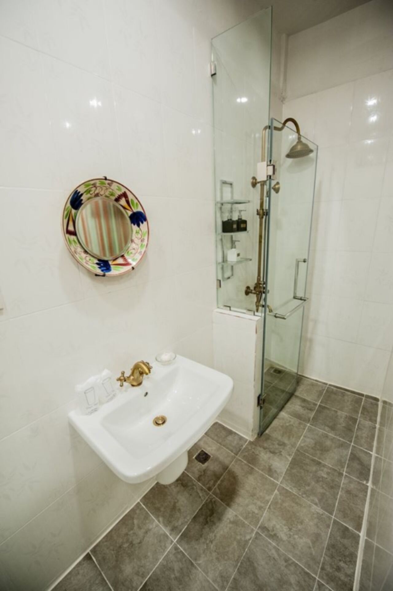 A bathroom with a white sink, a glass shower enclosure, and a decorative plate on the wall.
