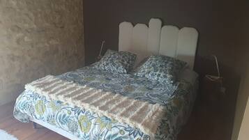 Una cama con colcha de estampado floral y dos almohadas a juego, un cabecero blanco y suelo de madera.