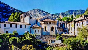 Un pueblo histórico con edificios de piedra, una iglesia destacada y abundante vegetación.