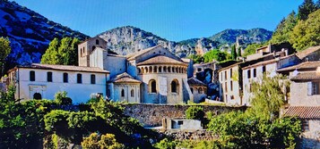 Un pueblo histórico con edificios de piedra, una iglesia destacada y abundante vegetación.