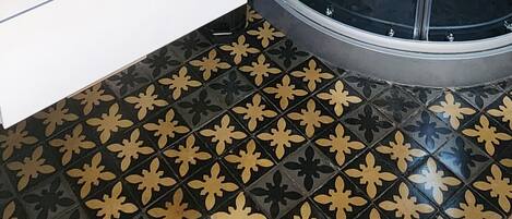 Un baño con ducha de vidrio, un lavamanos blanco y un espejo encima.