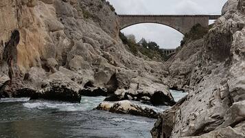Un lecho de río pedregoso con un puente al fondo.
