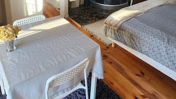 Een knus slaapkamer met een bed, een klein tafeltje met een vaas, een kledingkast en een douchehoek.