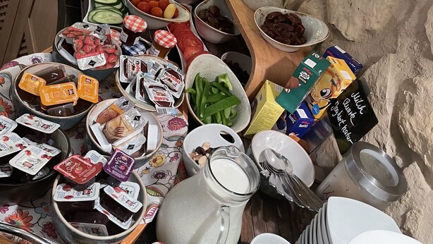 A buffet with various food items and condiments, arranged on a table against a stone wall backdrop. - Landgasthaus Zum Alten Fritz (Asbach)