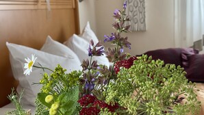 A hotel room with a bed, pillows, a bedside table, and a floral arrangement. - Landgasthaus Zum Alten Fritz (Asbach)