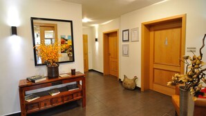 A hallway with wooden doors, a console table with books, a vase with flowers, and a mirror reflecting the room. - Landgasthaus Zum Alten Fritz (Asbach)