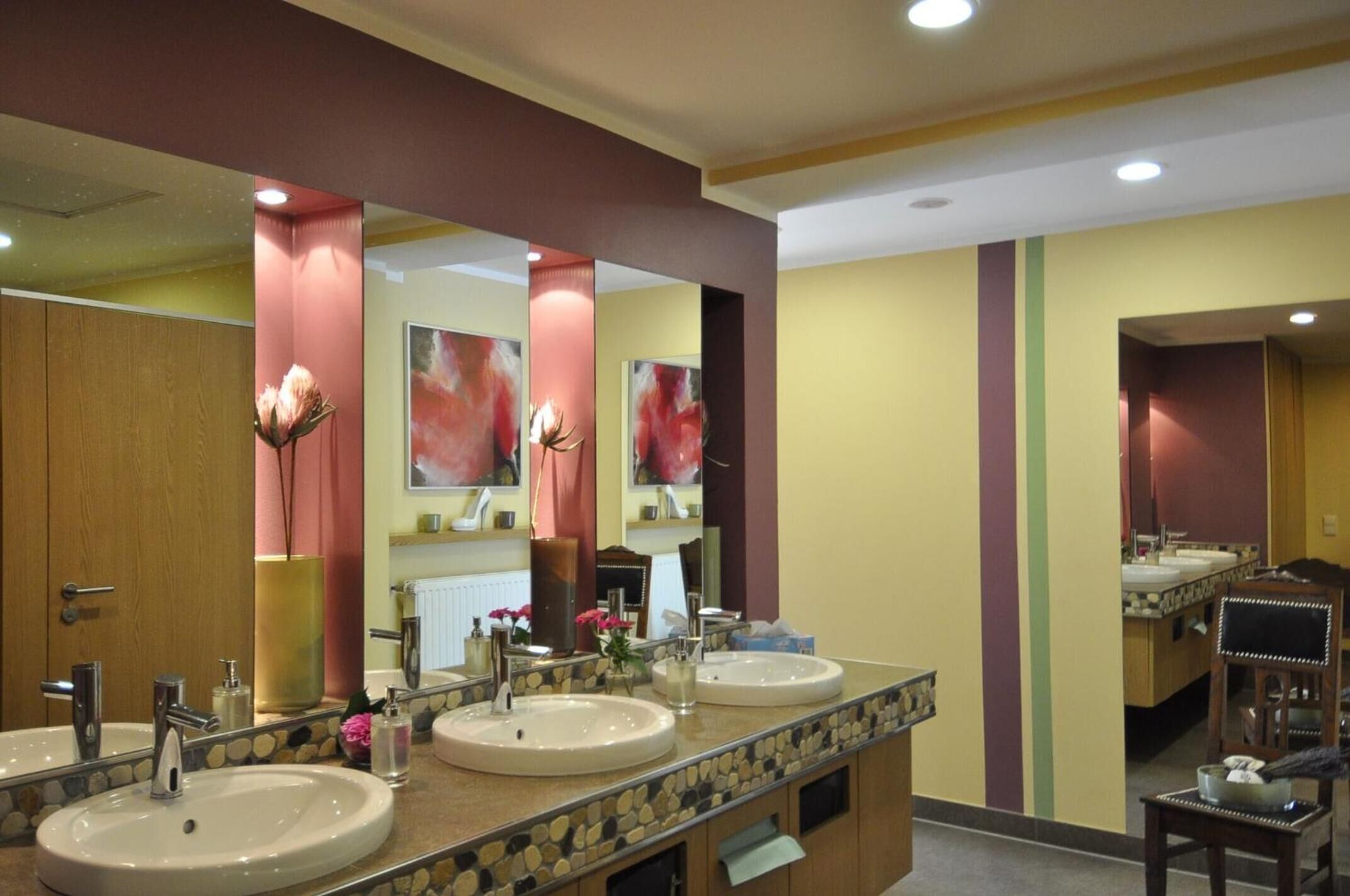 Un baño de hotel con dos lavamanos, un espejo grande y una puerta de madera.