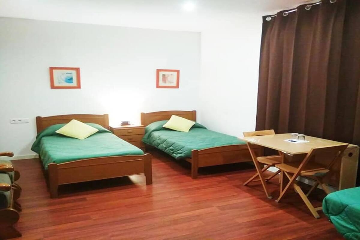 Ein Zimmer mit zwei Holzbett, einem Holztisch und einem Stuhl.