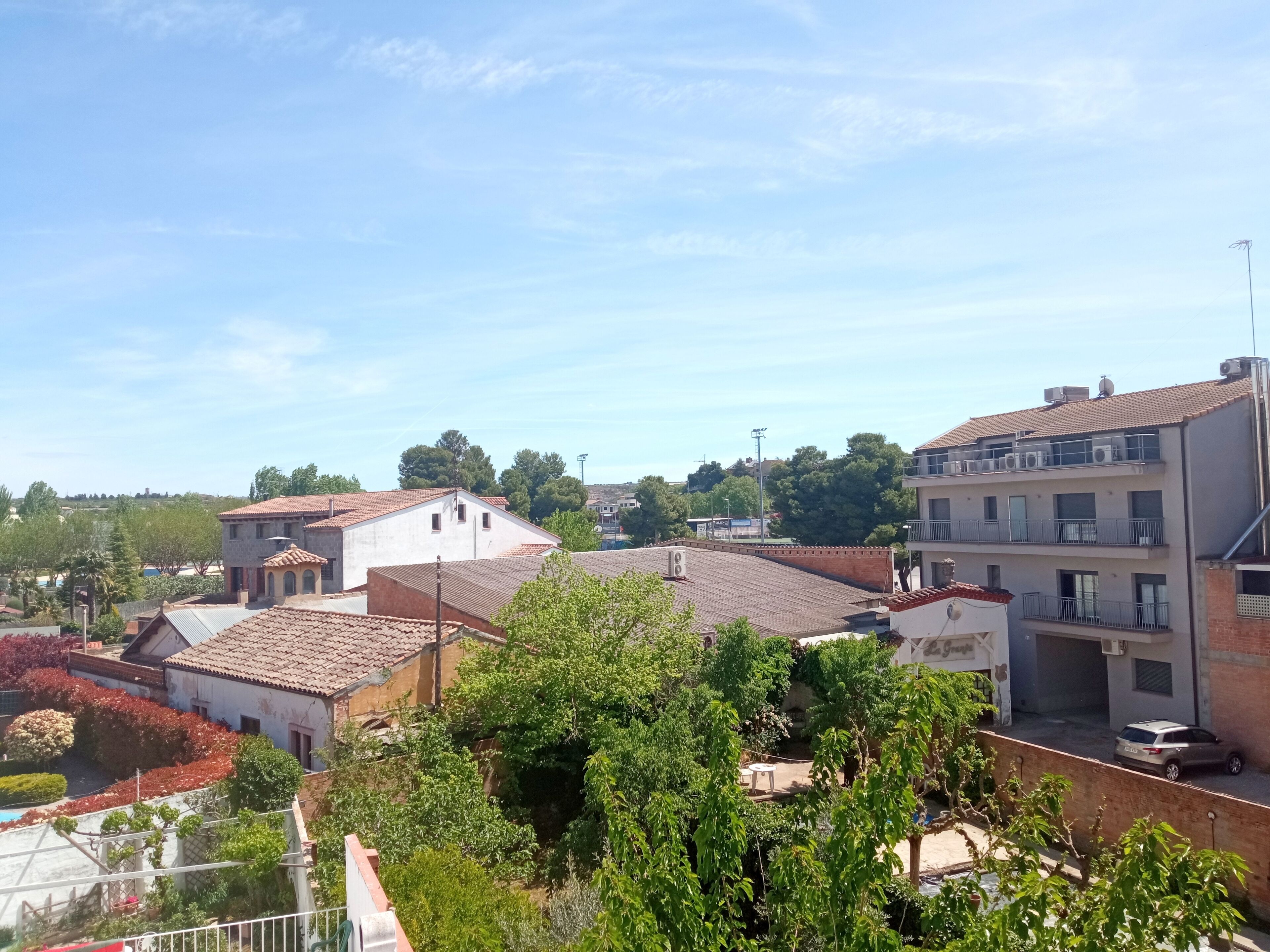 Zona residencial con casas de tejados rojos, rodeada de vegetación y árboles.