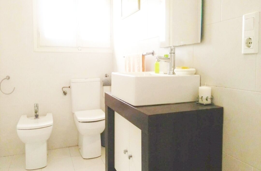 Un baño con inodoro, bidé y lavabo con espejo.