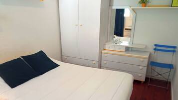 A bedroom with a bed, a wardrobe, a dresser, a mirror, and a chair.