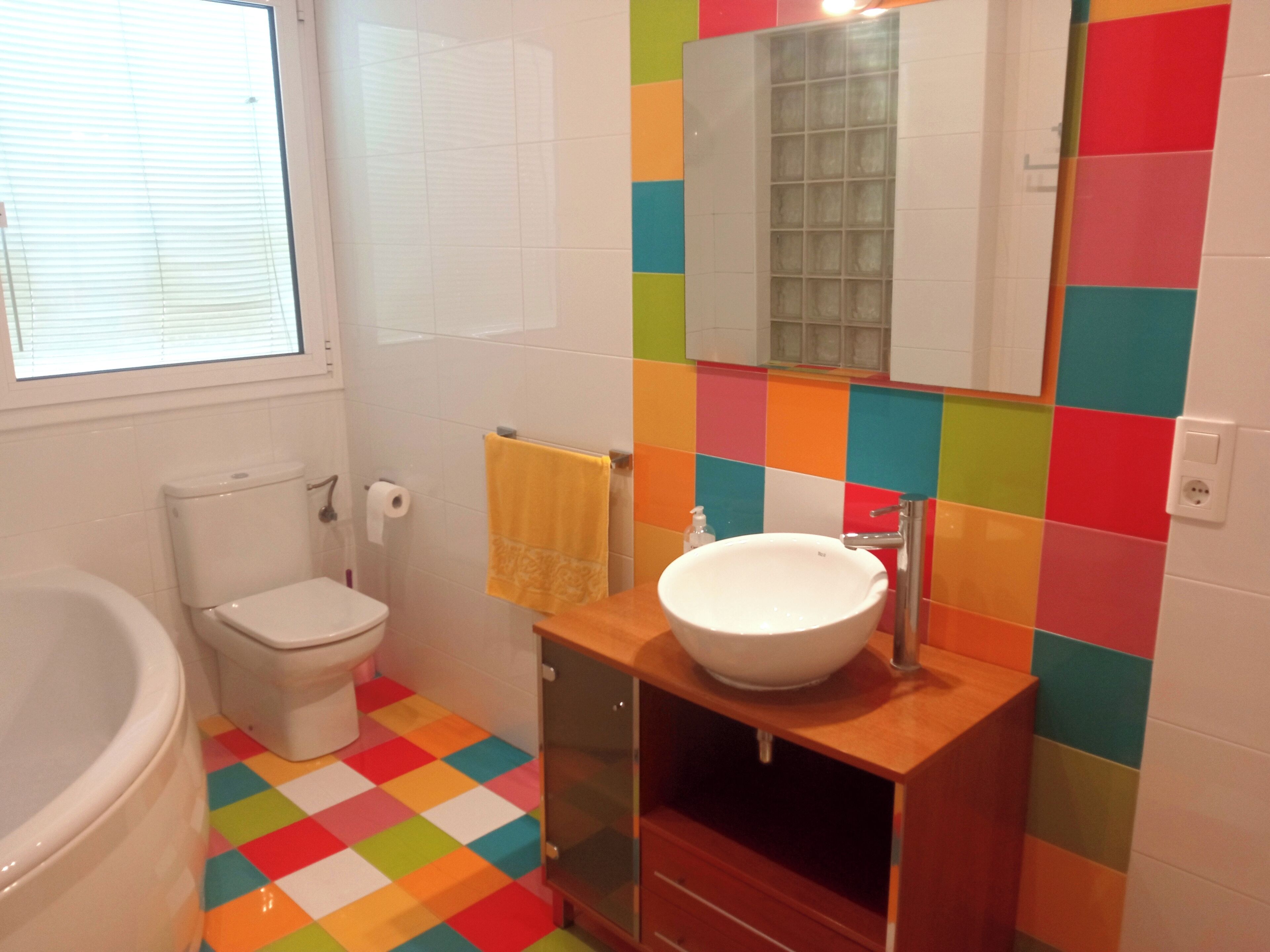 A bathroom with a white toilet, a white sink, and a colorful checkered floor.