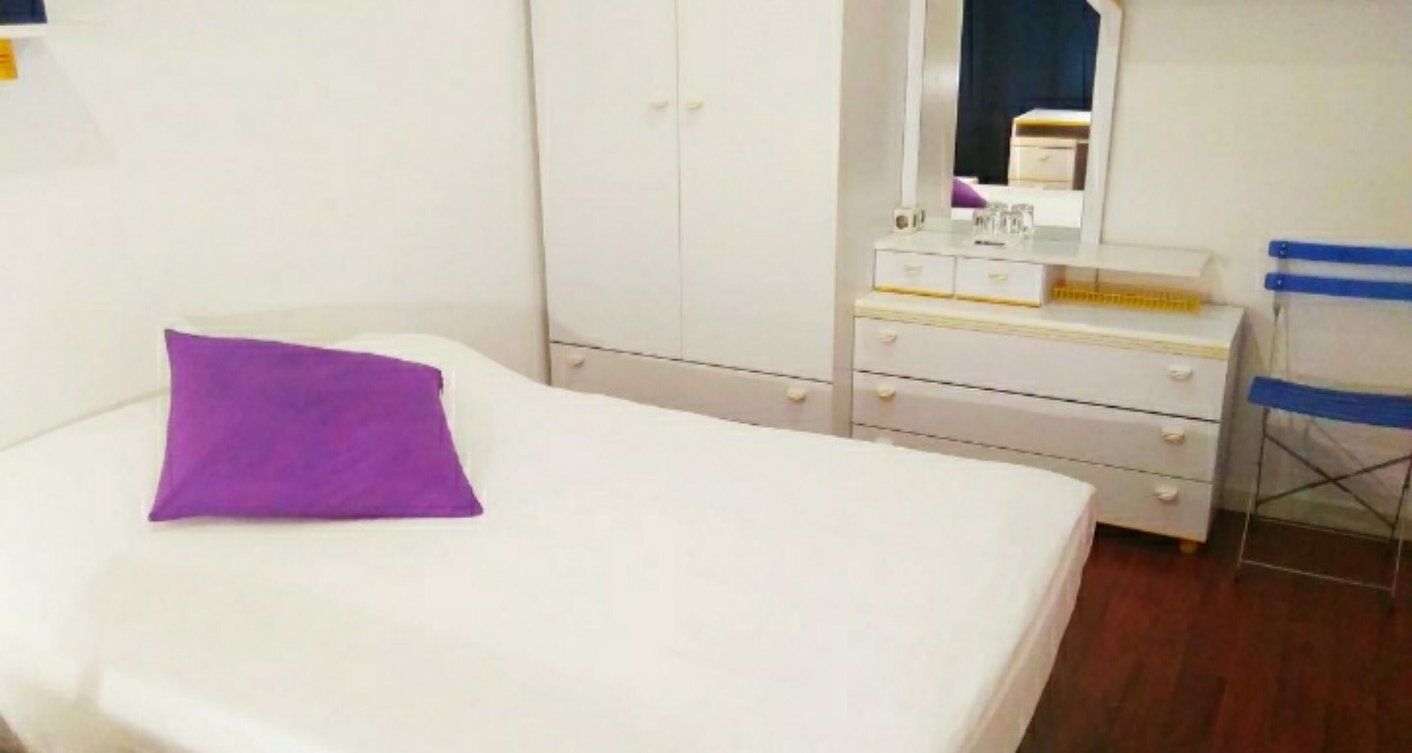 Un dormitorio con cama, cómoda, espejo y silla.