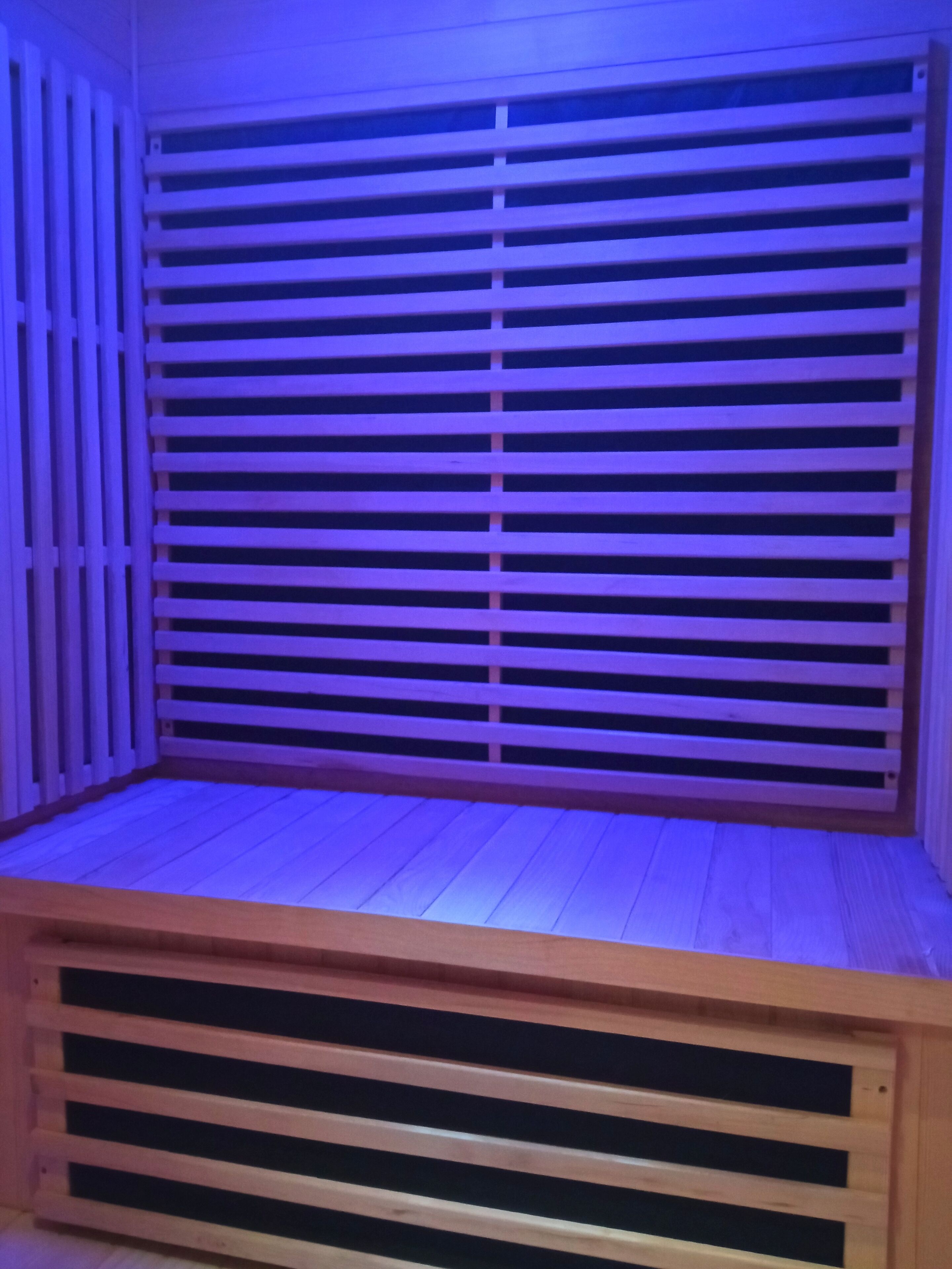A room with a slatted wooden partition and a wooden bench.