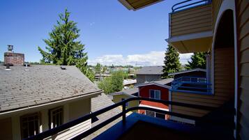 A residential building with a balcony, a chimney, and a view of neighboring houses and trees.