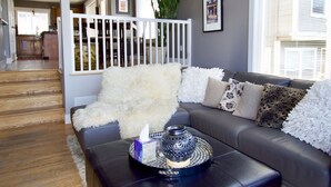 A living room with a dark leather sofa, a white furry throw, and a decorative tray. - Comfort and Grace on Queen Anne Hill (Seattle)