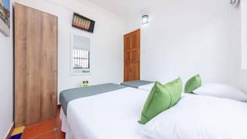 Habitación de hotel con dos camas, un armario de madera, un espejo y un televisor en la pared.