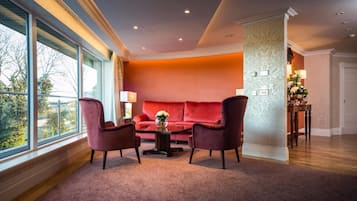 A room with a red sofa, two armchairs, a coffee table, and a view through large windows.