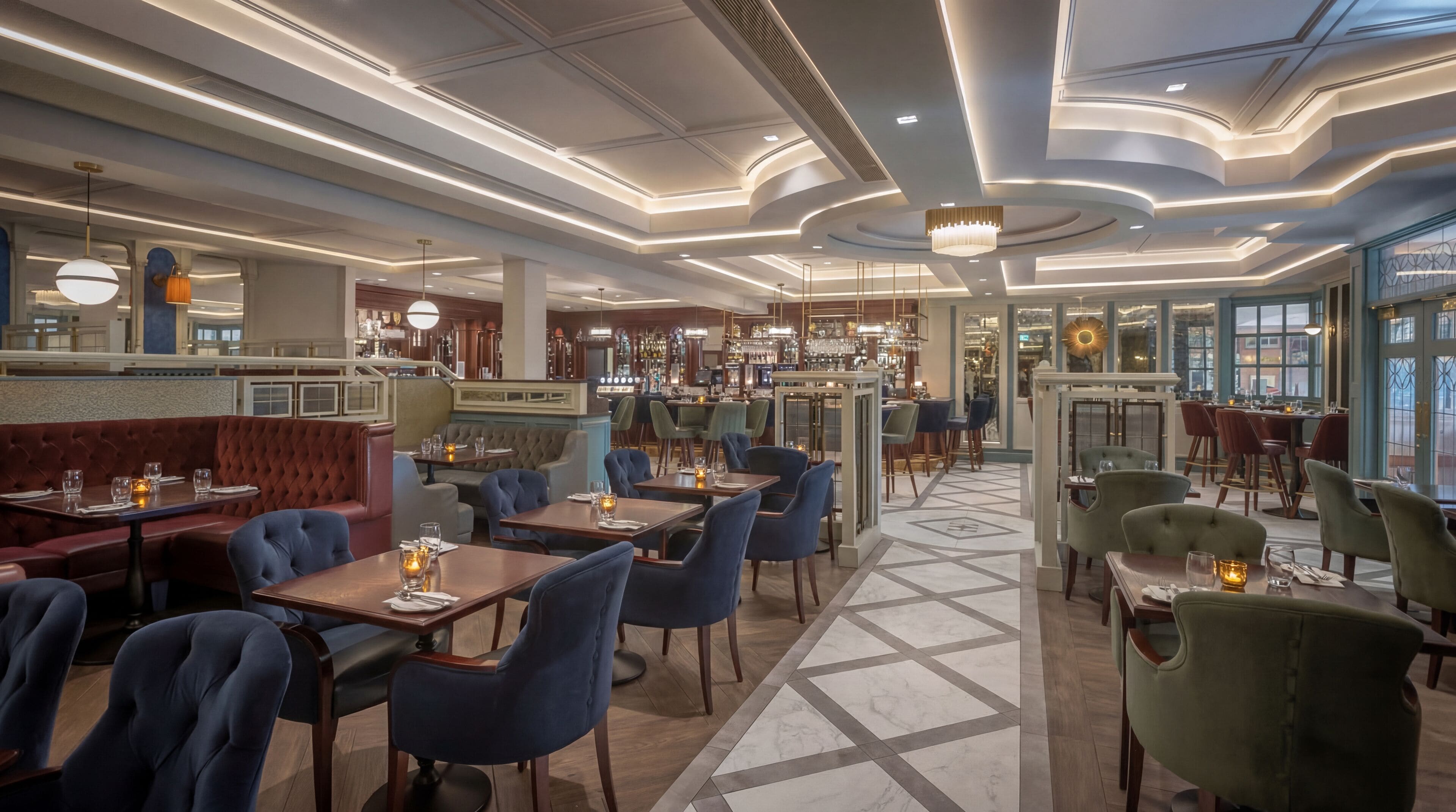 Un restaurant doté d’un bar, de différents types de tables et de chaises, et d’un sol à motifs.