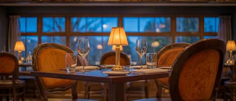 A restaurant interior with a table set for four, including wine glasses and a lamp.