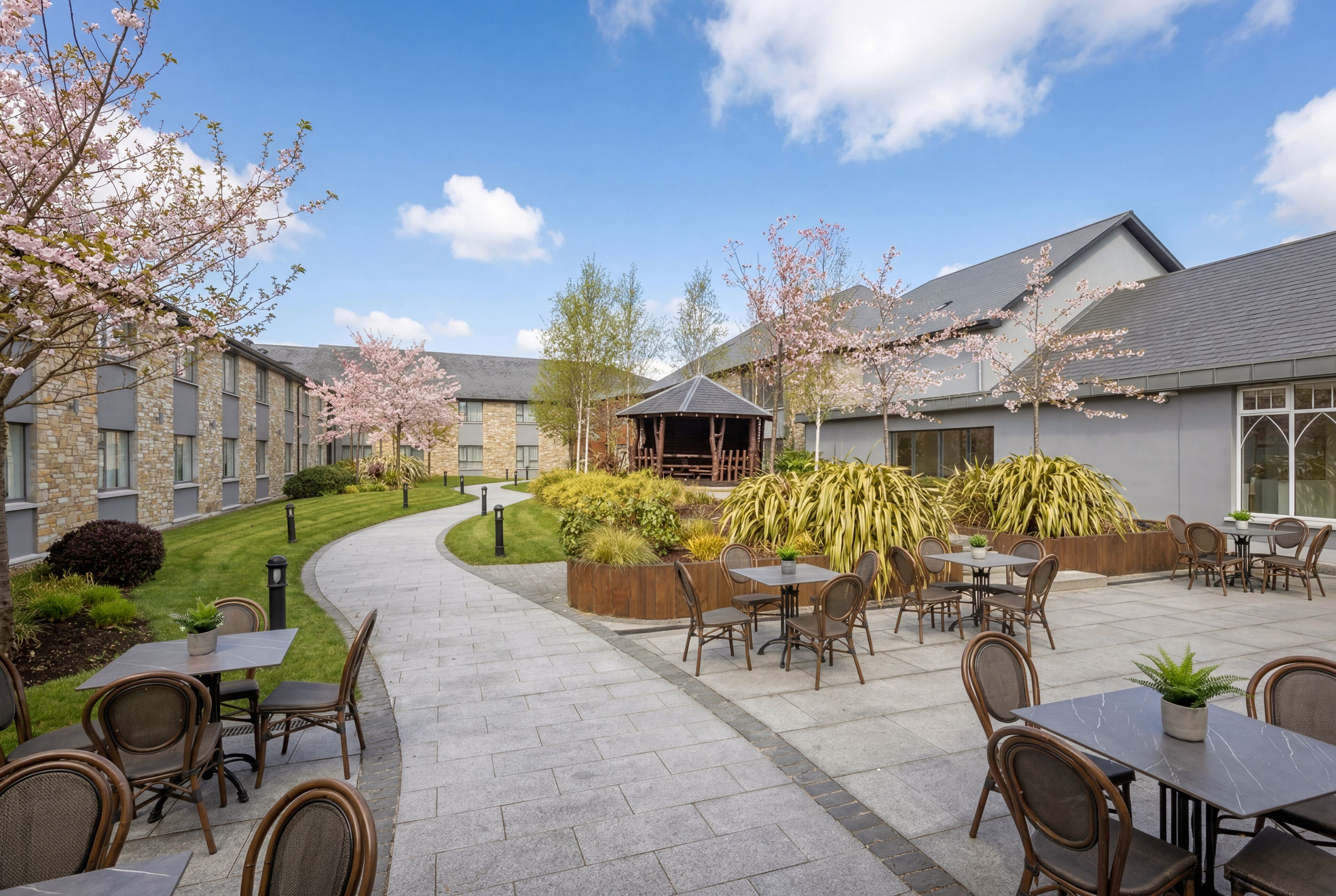 A courtyard with outdoor seating, a gazebo, and a building with stone and brick architecture.