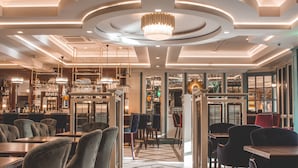 Un interior de restaurante moderno con una lámpara central, varias mesas de comedor y un suelo estampado.