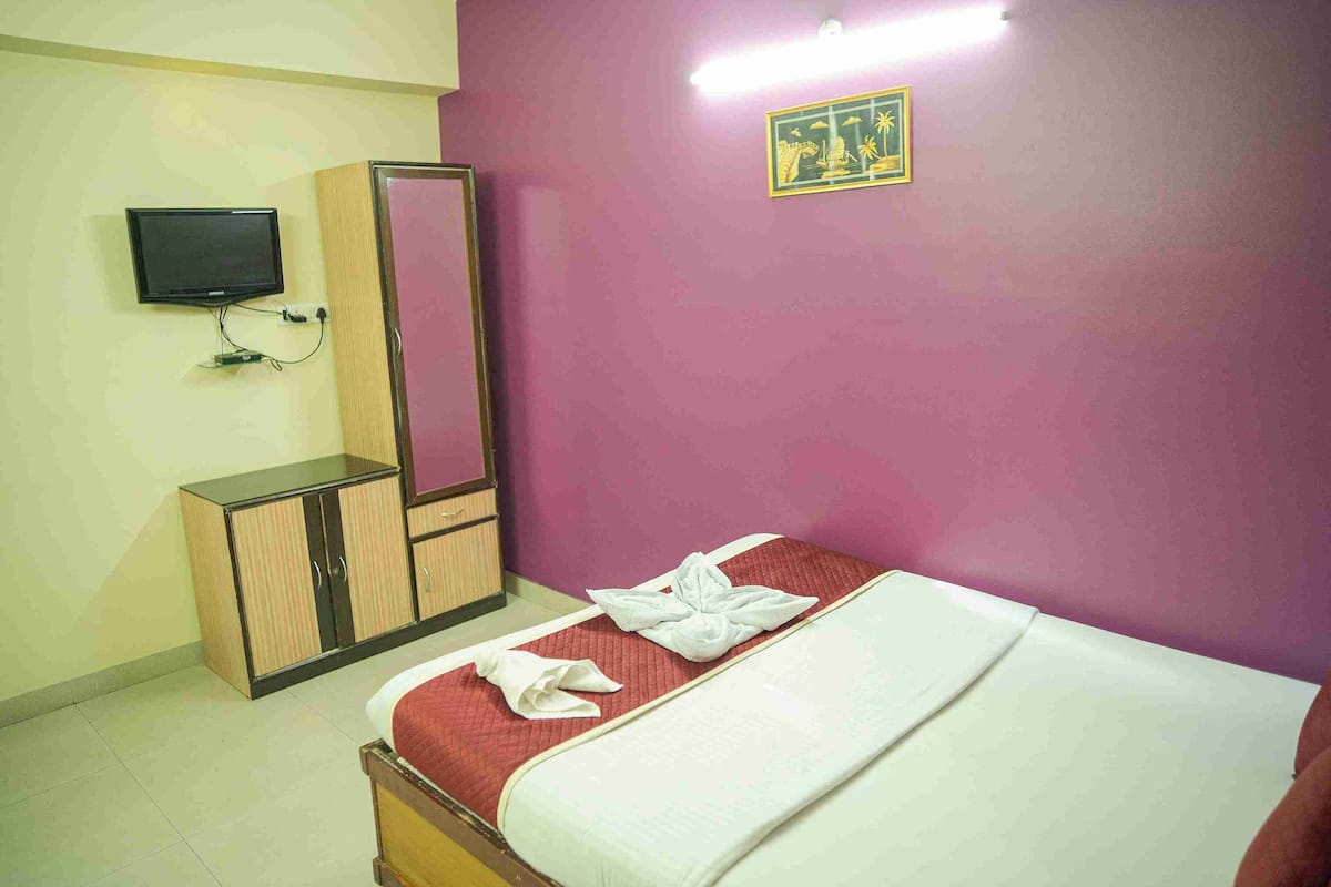 Habitación de hotel con cama, armario, televisor y un adorno en la pared.
