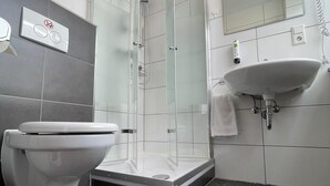 A modern bathroom with a glass-enclosed shower, a white sink, and a toilet. - MOTELO Bielefeld (Bielefeld)