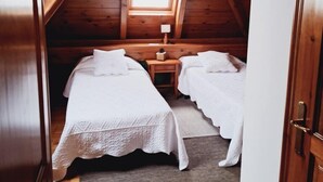 Une petite chambre mansardée, chaleureuse et accueillante, avec deux lits, une fenêtre et une table de chevet.