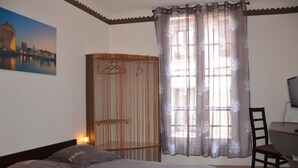A bedroom with a bed, a desk with a chair, a wardrobe, and a window with sheer curtains. - B&B La Maison d'Olivier (Beaucaire)