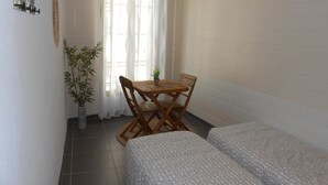 A small room with two beds, a wooden table with chairs, a potted plant, and a window with curtains. - B&B La Maison d'Olivier (Beaucaire)