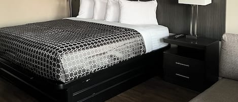 A hotel room with a bed, bedside tables, a lamp, and a chair.