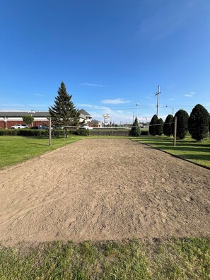 A baseball field with a dirt infield and grass outfield, surrounded by trees and buildings.