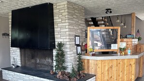 A modern interior with a stone fireplace, a wooden reception desk, and a large flat-screen TV mounted on the wall. - Lake Erie Lodge (Erie)