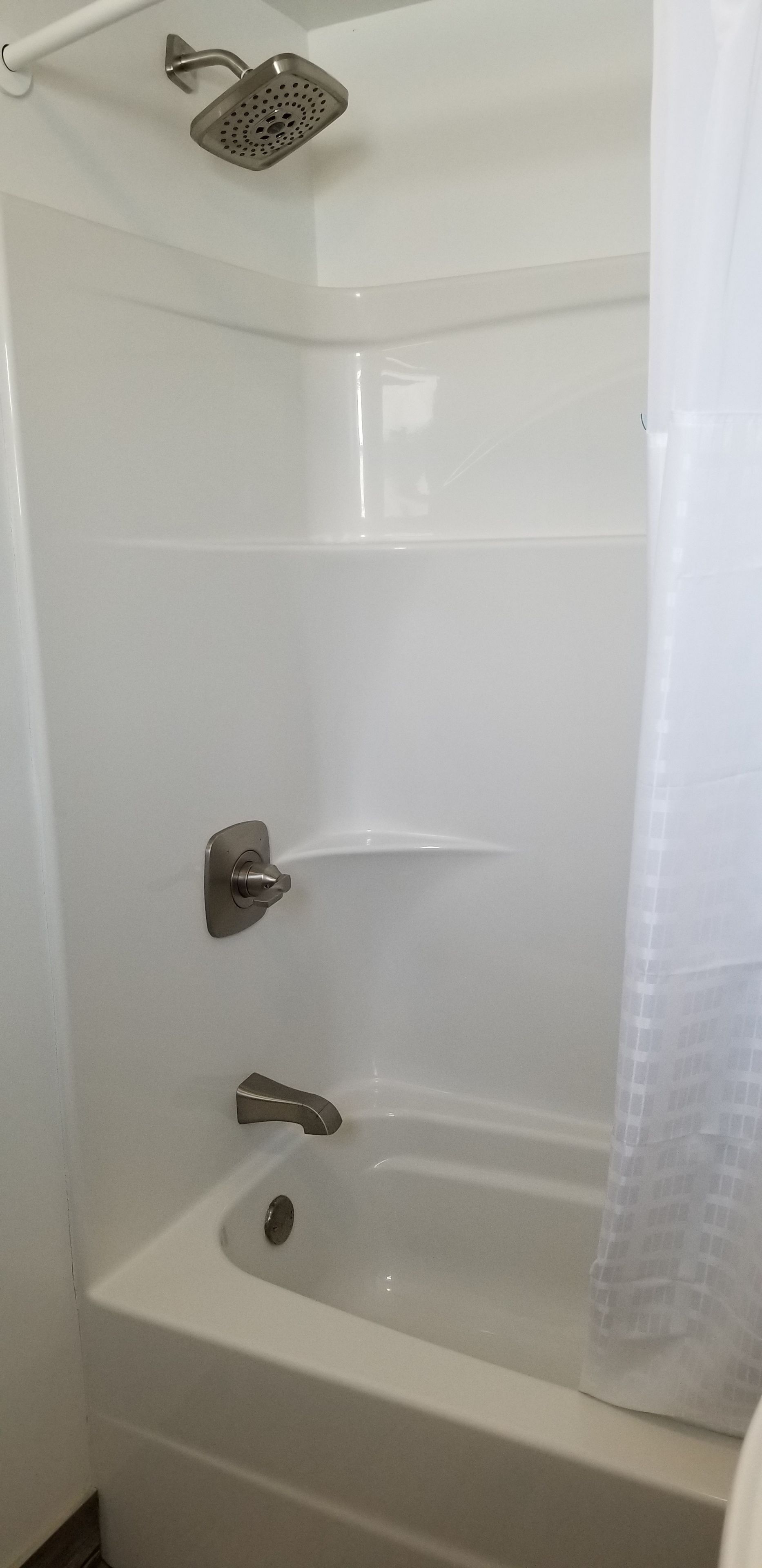 Une baignoire blanche avec un pommeau de douche et un rideau.
