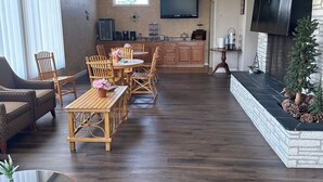 A spacious living room with a fireplace, wooden furniture, and a flat-screen TV mounted on the wall. - Lake Erie Lodge (Erie)